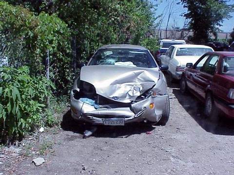 Photo of a silver car with a wrecked front end. The car is parked in a lot with other cars. Torts is mostly about car crashes.